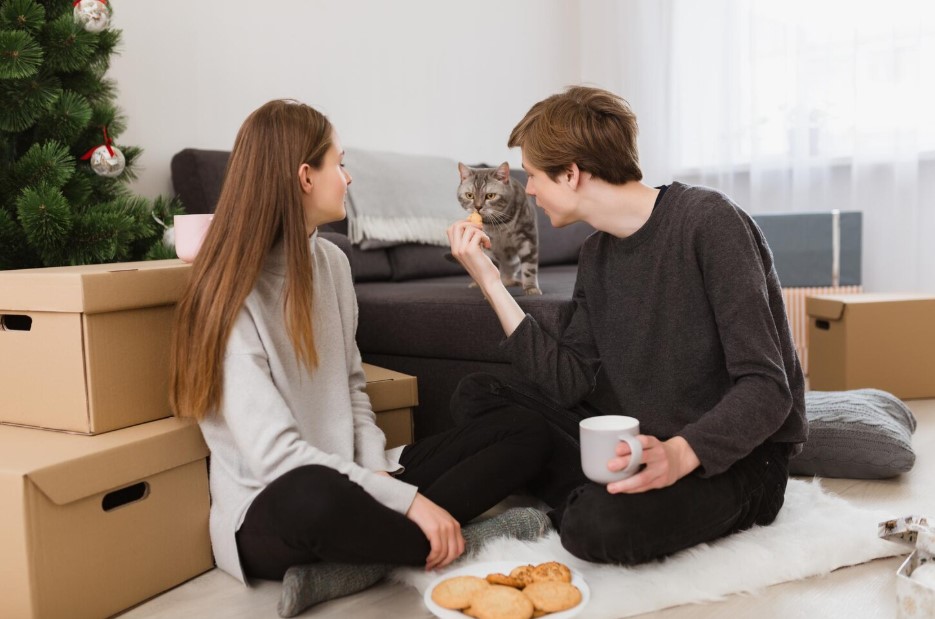 couple sitting on floor at new apartment with pet cat