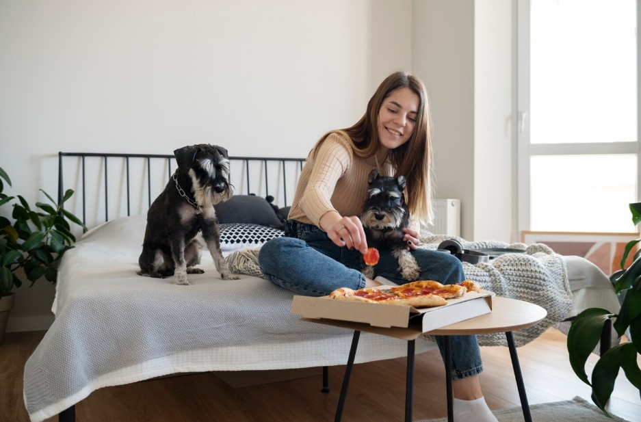 Young woman eating pizza on bed