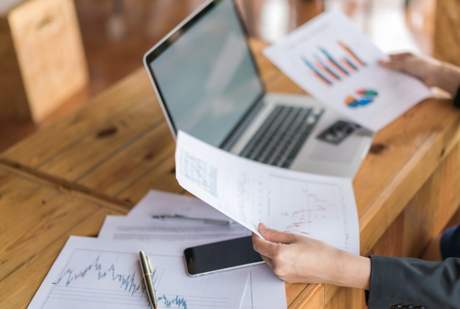 woman hand with financial charts and laptop on the table 