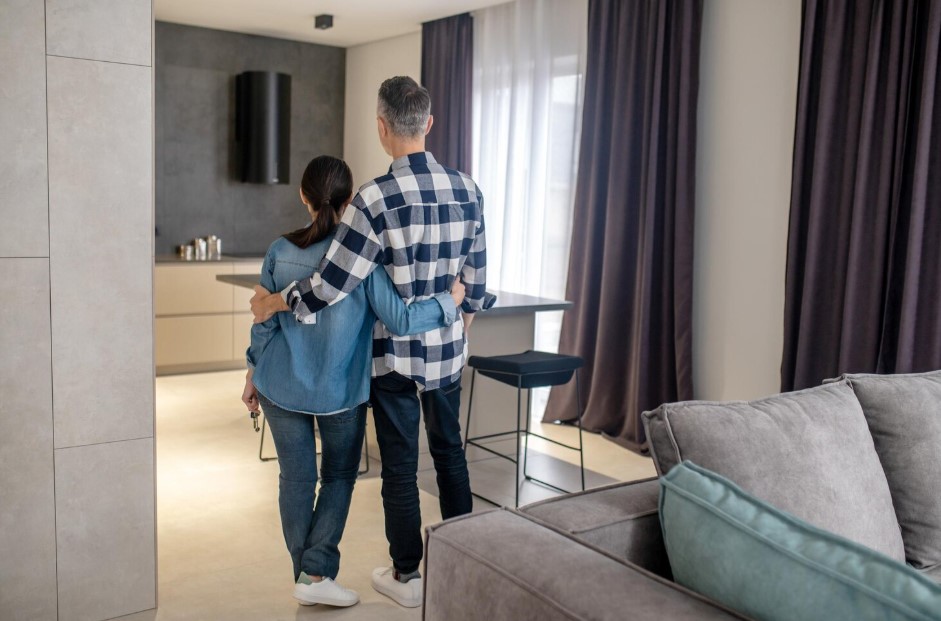 New house back view of man and woman holding keys in hand standing in new modern house
