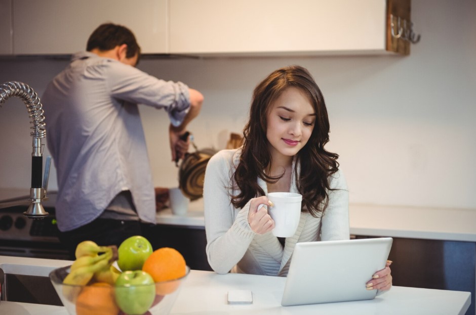 Woman using digital tablet while man working in background