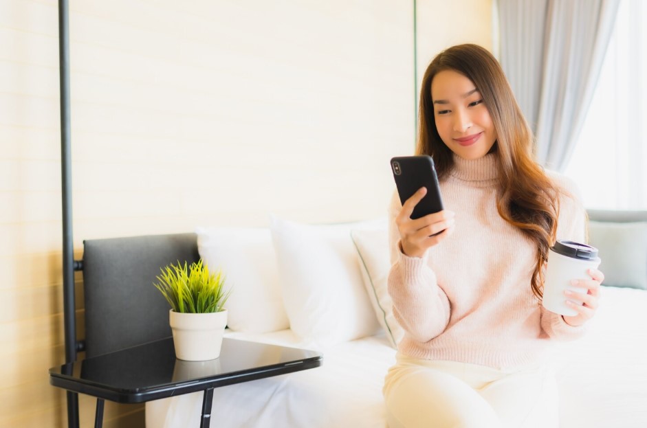 Portrait beautiful young asian woman with coffee cup and mobile phone on bed
