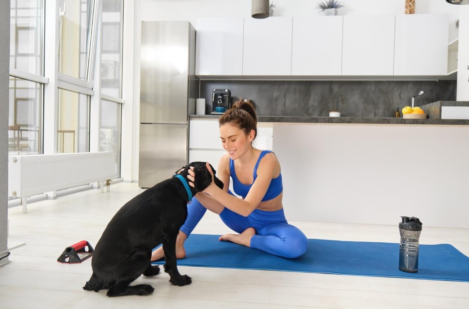 Portrait of smiling beautiful woman doing sports workout from home with her black dog doing sports in living room