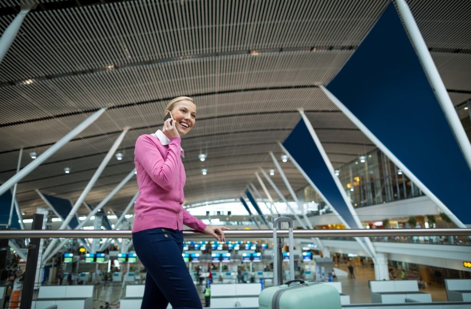 Female commuter with luggage talking on mobile phone