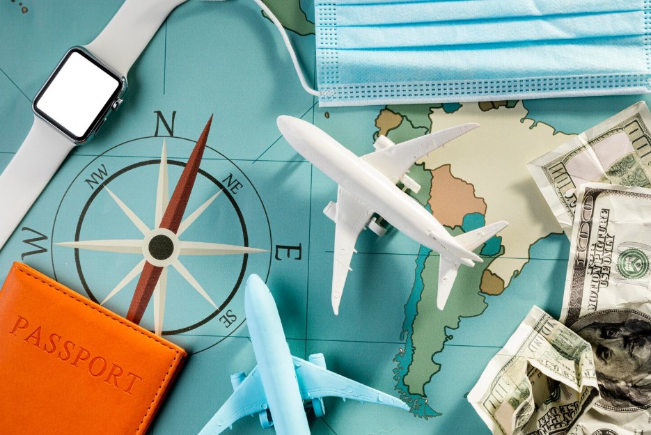 Top view of airplane figurines with smartwatch and medical mask