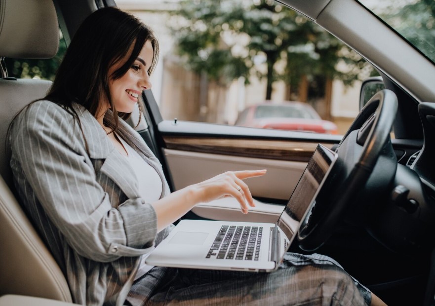 Businesswoman with a laptop in her car in the street