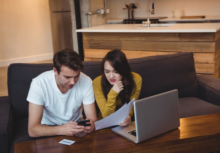 Couple sitting on sofa discussing with financial documents in living room
